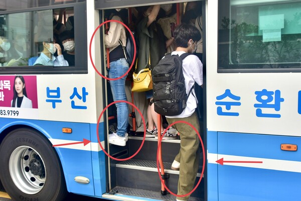 One student (left side) is hanging onto the railing with her toes, while the other is standing on the lower stairs, trying to get out for the person who gets on and off. [Jun Hyung-Seo, Reporter]