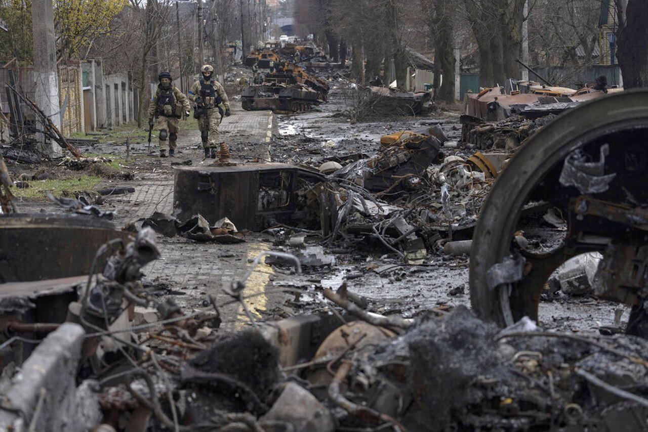 Soldiers walk between destroyed tanks in Kyiv, Ukraine