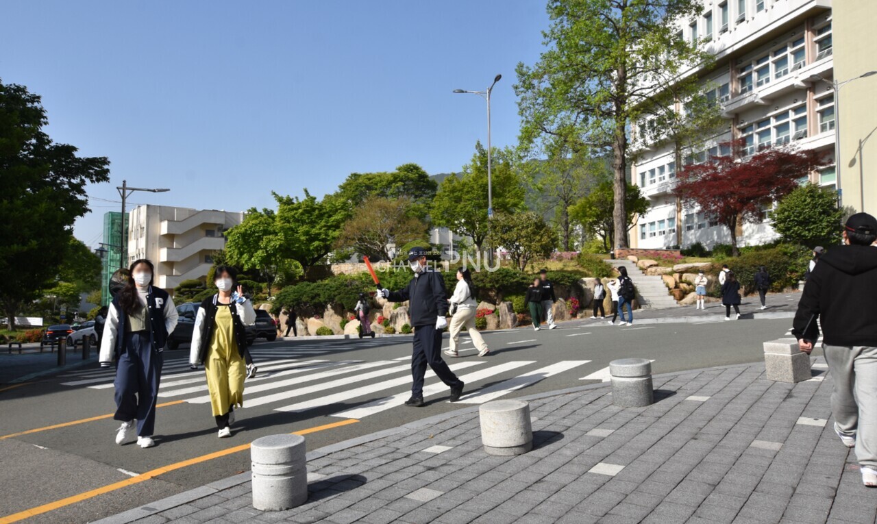 지난 4월 24일 주차관리원이 정리 중인 새벽벌도서관 앞 도로를 보행자들이 횡단하는 모습이다. [최선우 기자]