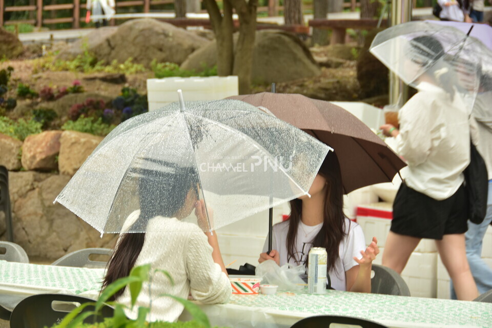 지난 18일, 학생들이 우산을 쓰고 푸드트럭의 음식을 즐기고 있다. [정혜은 기자]