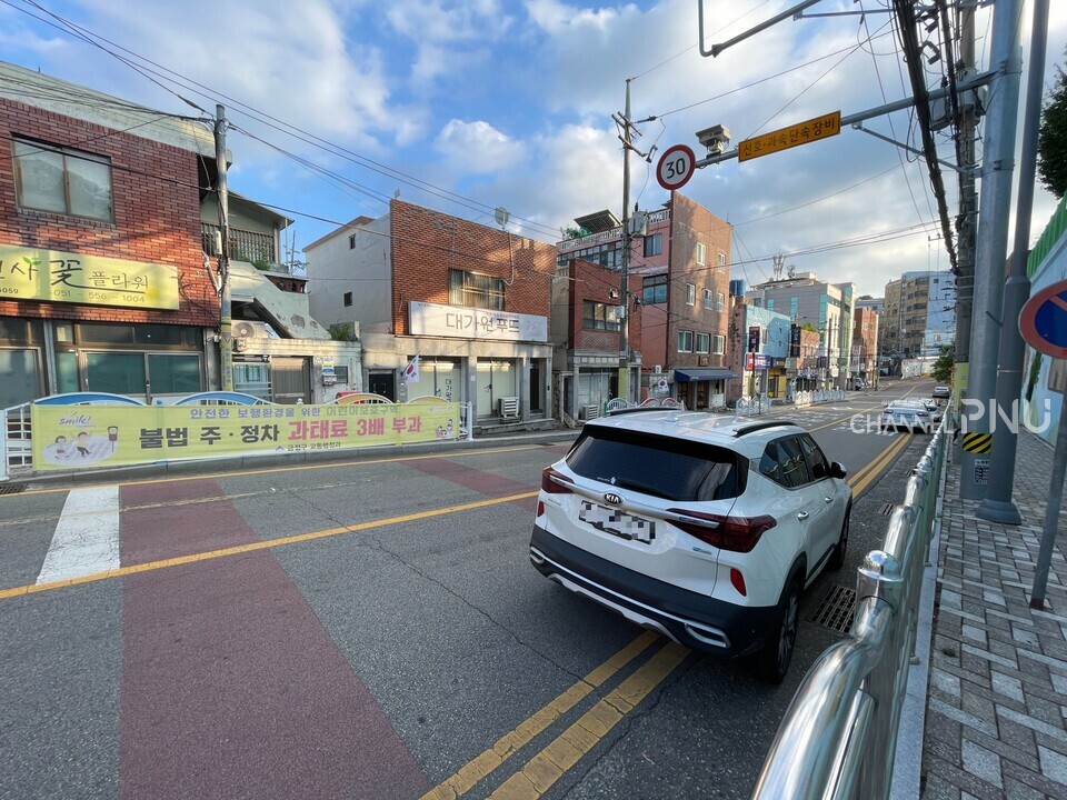 On August 15, in front of Seodong Elementary School, a banner titled "Imposing an Illegal Parking Penalty" was hung, but cars were still parked on the road. [You Seung-Hyun, Reporter]
