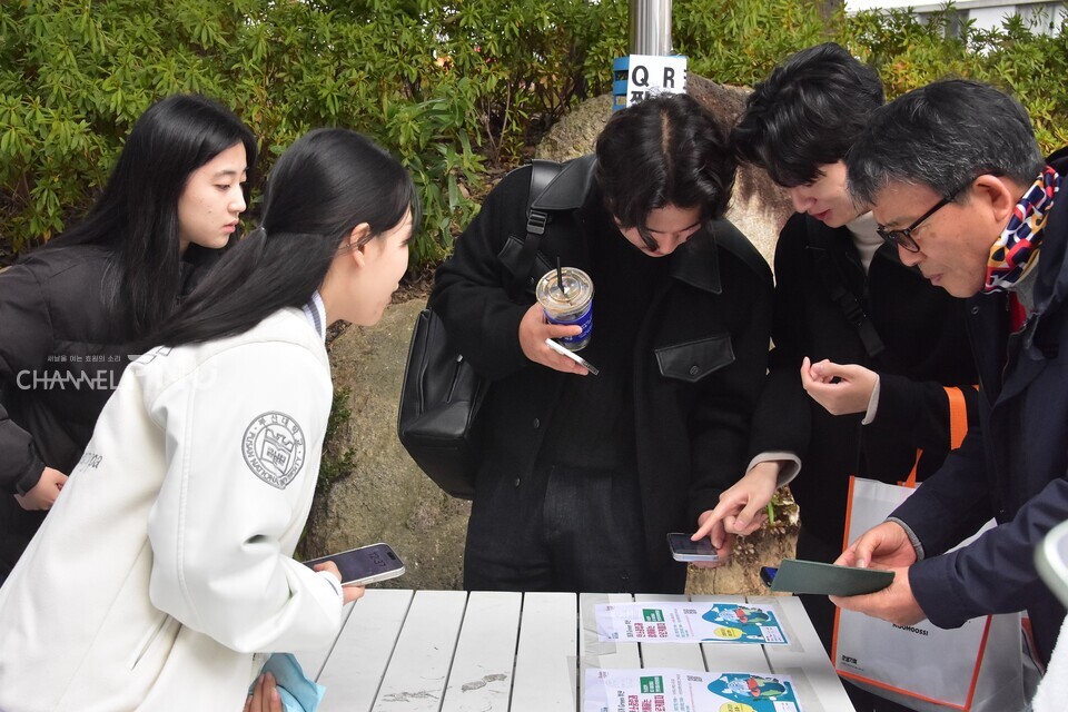 맑음 부원들이 행사 참여자들에게 부산시 탄소중립 정책과 관련한 설문조사 QR코드를 안내하고 있다. [최유민 기자]