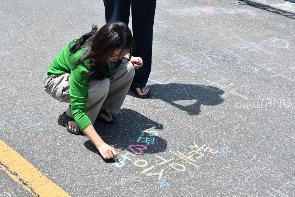 29일 제6공학관과 시월광장 사이에 마련된 '낙서 도로'에서 학생이 제공된 분필로 문구를 쓰고 있다. [이수현 기자]