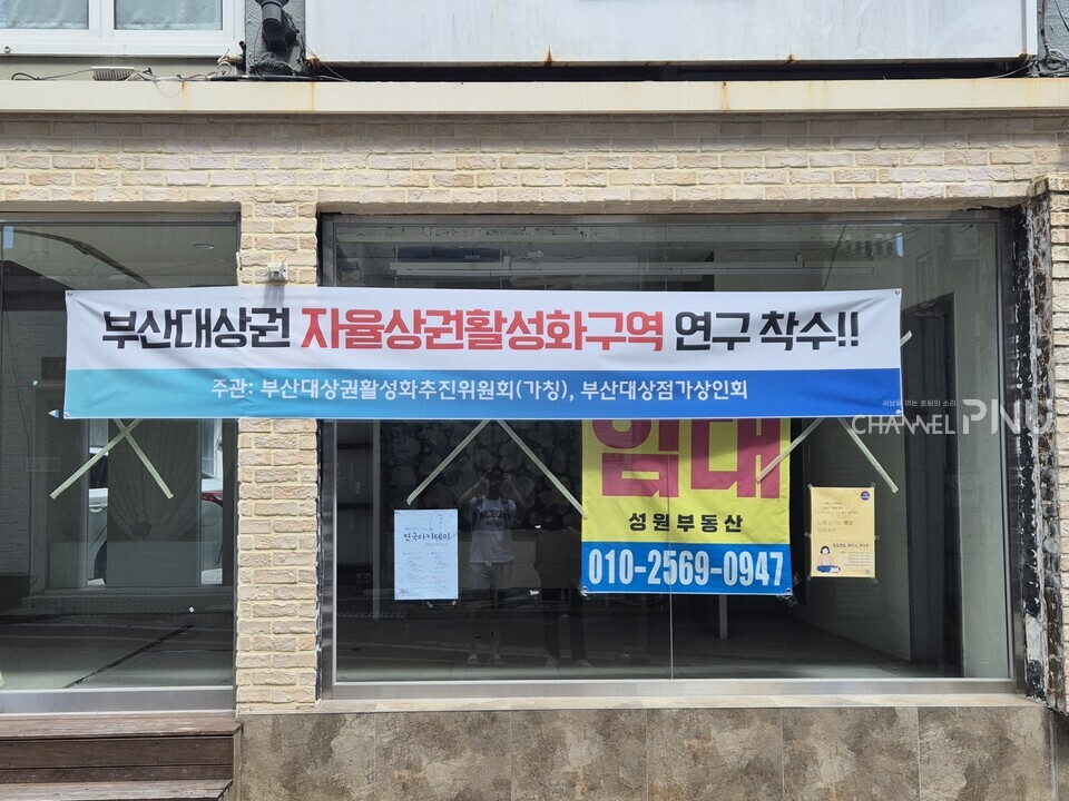 부산대 앞 상점이 즐비해 있는 금정로60번길에 부산대상권 자율상권활성화구역 연구가 착수됐다는 현수막이 붙어 있다. [유승현 보도부장]
