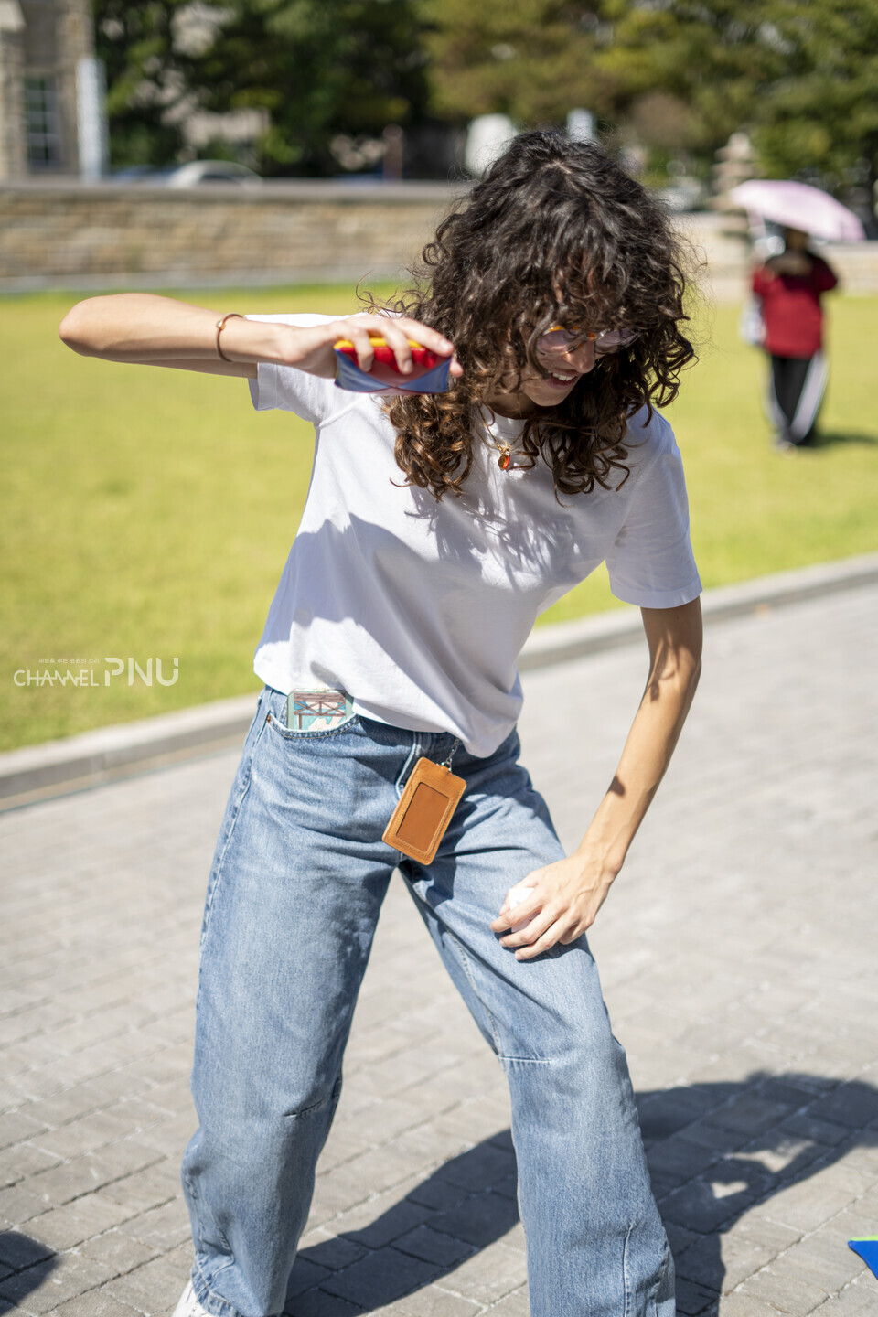 지난 10월 1일 열린 ‘PNU K-Festival’에서 한 외국인 유학생이 박물관 새벽뜰 앞 부스에서 딱지치기를 즐기며 한국 전통 놀이 문화를 체험하고 있다. [임현규 전문기자]