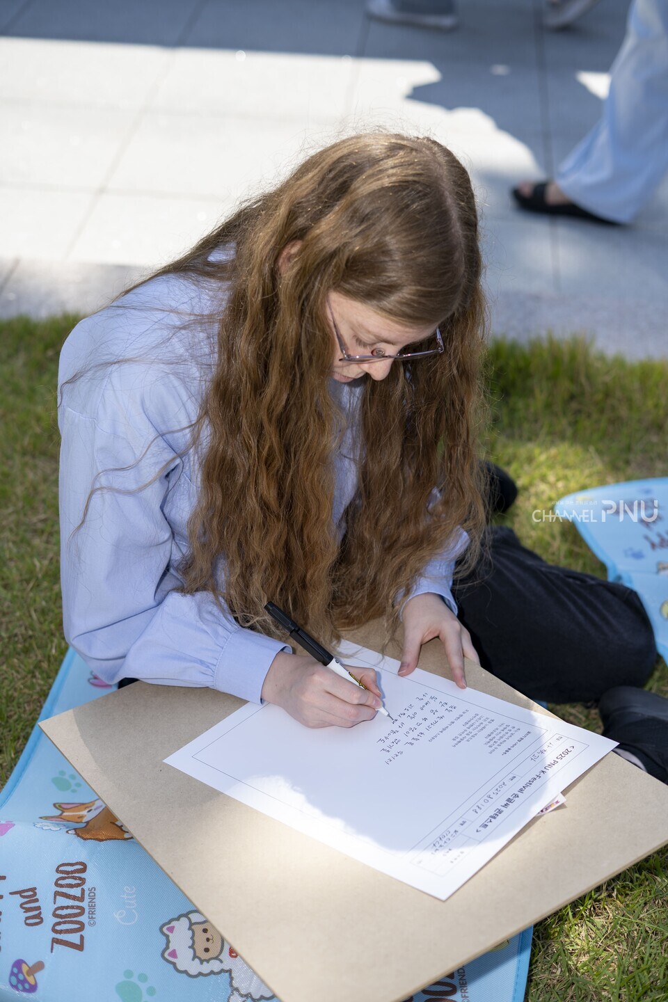 지난 10월 1일 열린 ‘PNU K-Festival’에서 한 외국인 유학생이 새벽뜰에 앉아 ‘손글씨 콘테스트’에 참여하고 있다. [임현규 전문기자]