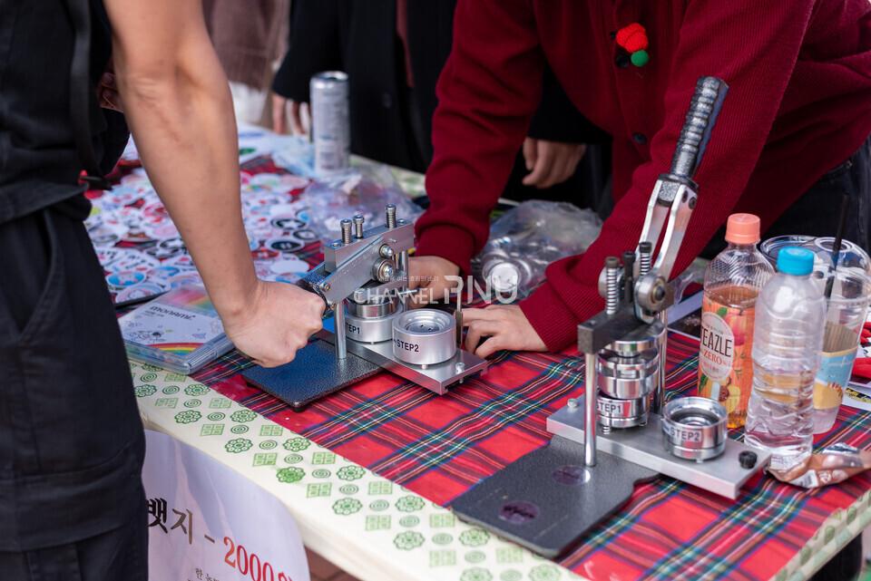 지난 10월 30일 우리 대학 시월광장 넉넉한 터에서 열린 SPOT 연합 축제 부스에서 한 학생이 뱃지 만들기 체험을 하고 있다.  [송민수 기자]